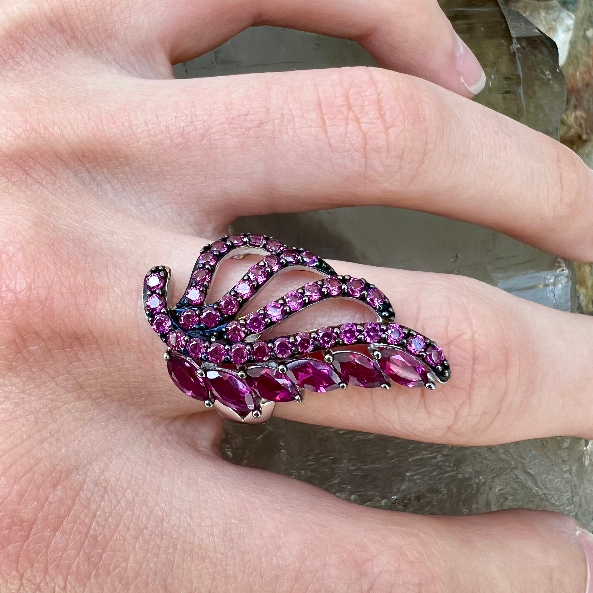 A sterling silver, feather shaped ring set with round and marquise cut rhodolite garnet stones.