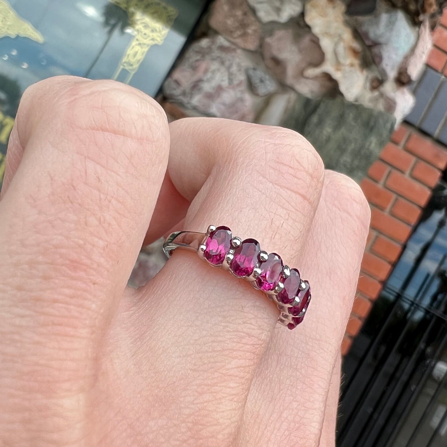 A sterling silver band set with 7 oval cut, purple rhodolite garnet stones.