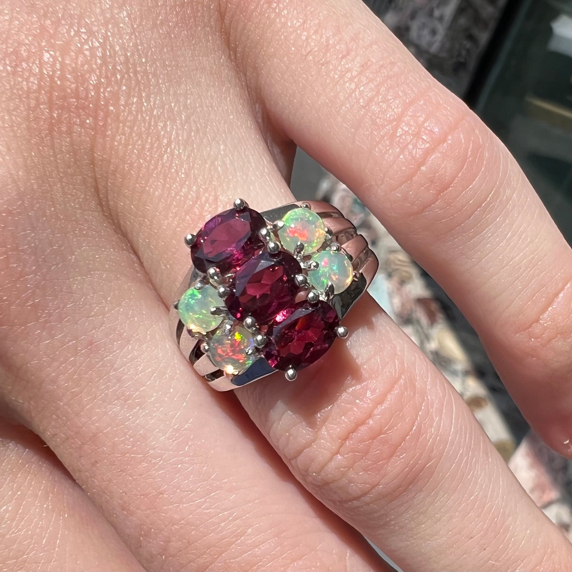 A sterling silver ring set with three oval cut rhodolite garnets and four round cabochon cut Ethiopian opals.