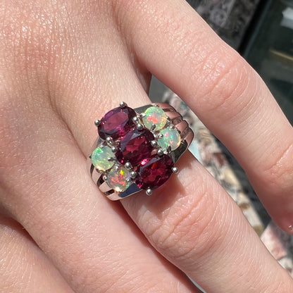 A sterling silver ring set with three oval cut rhodolite garnets and four round cabochon cut Ethiopian opals.