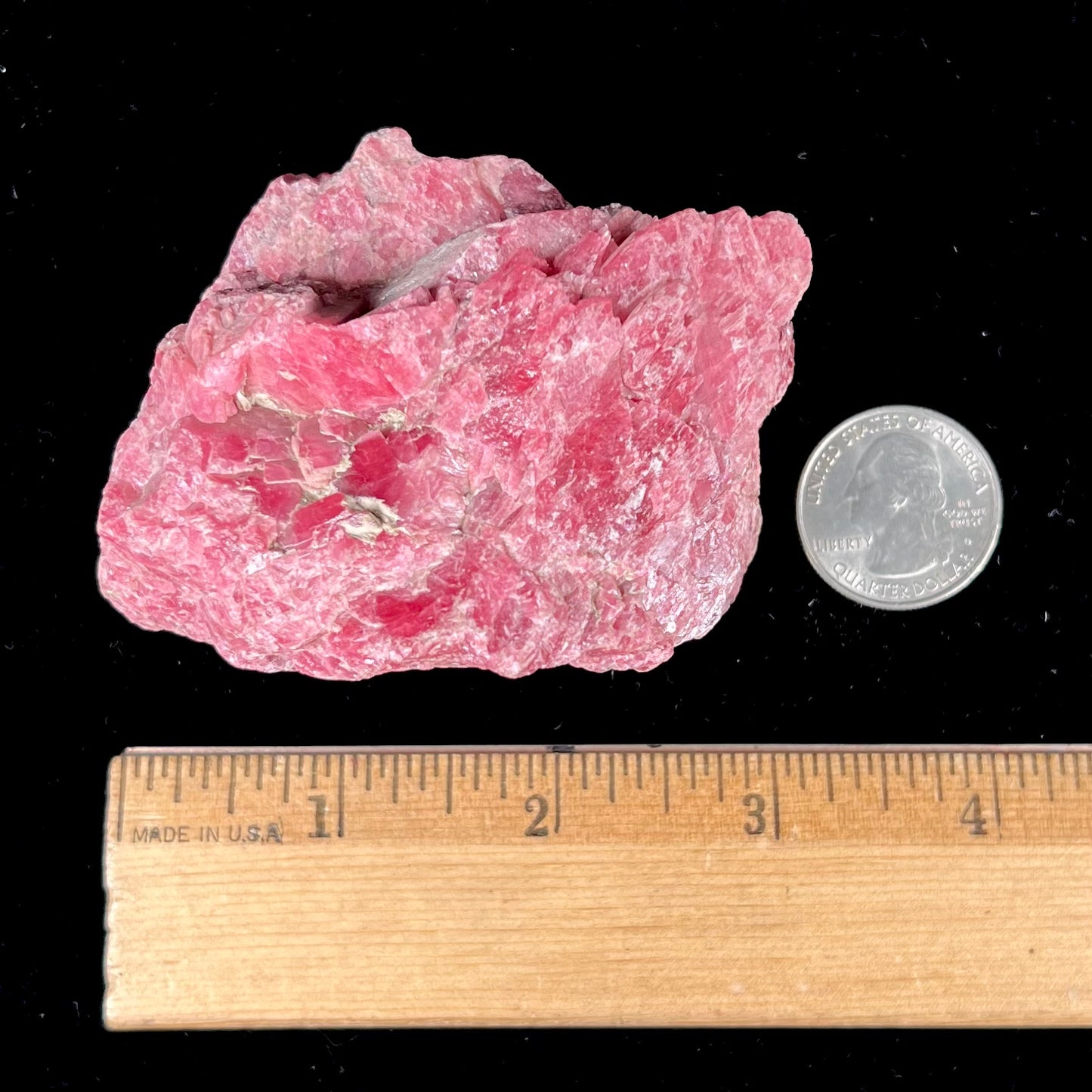 A rough pink rhodonite crystal specimen the size of a small fist.