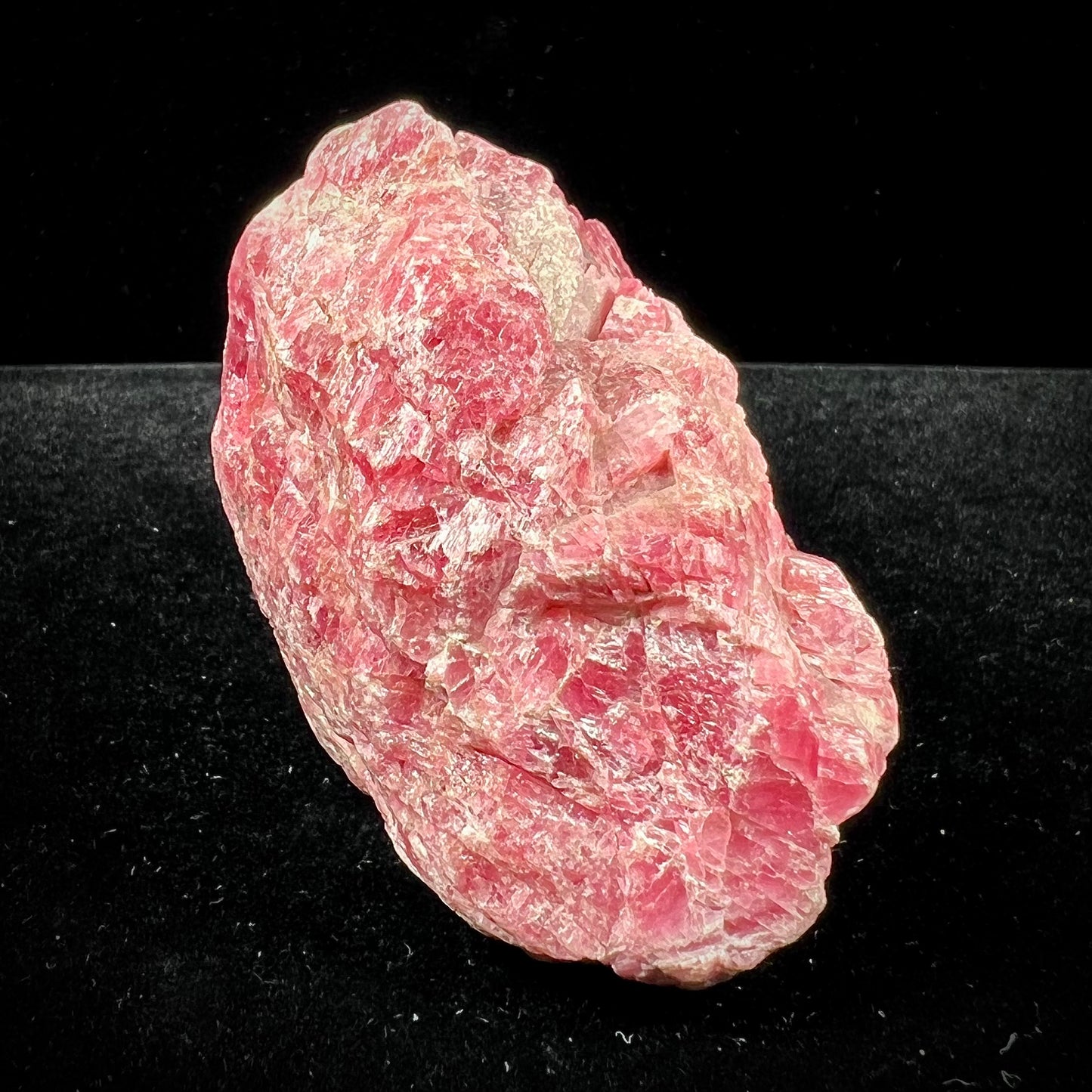 A rough pink rhodonite crystal specimen the size of a small fist.