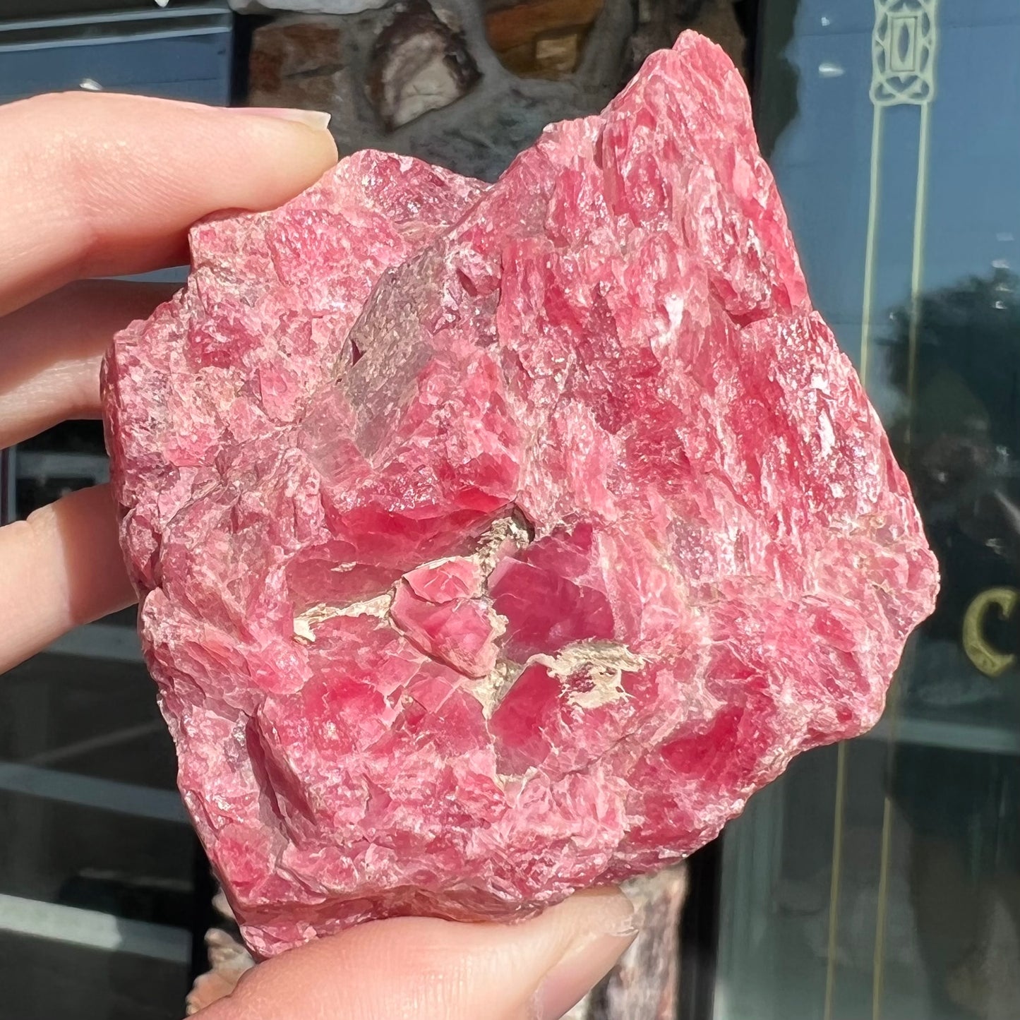 A rough pink rhodonite crystal specimen the size of a small fist.
