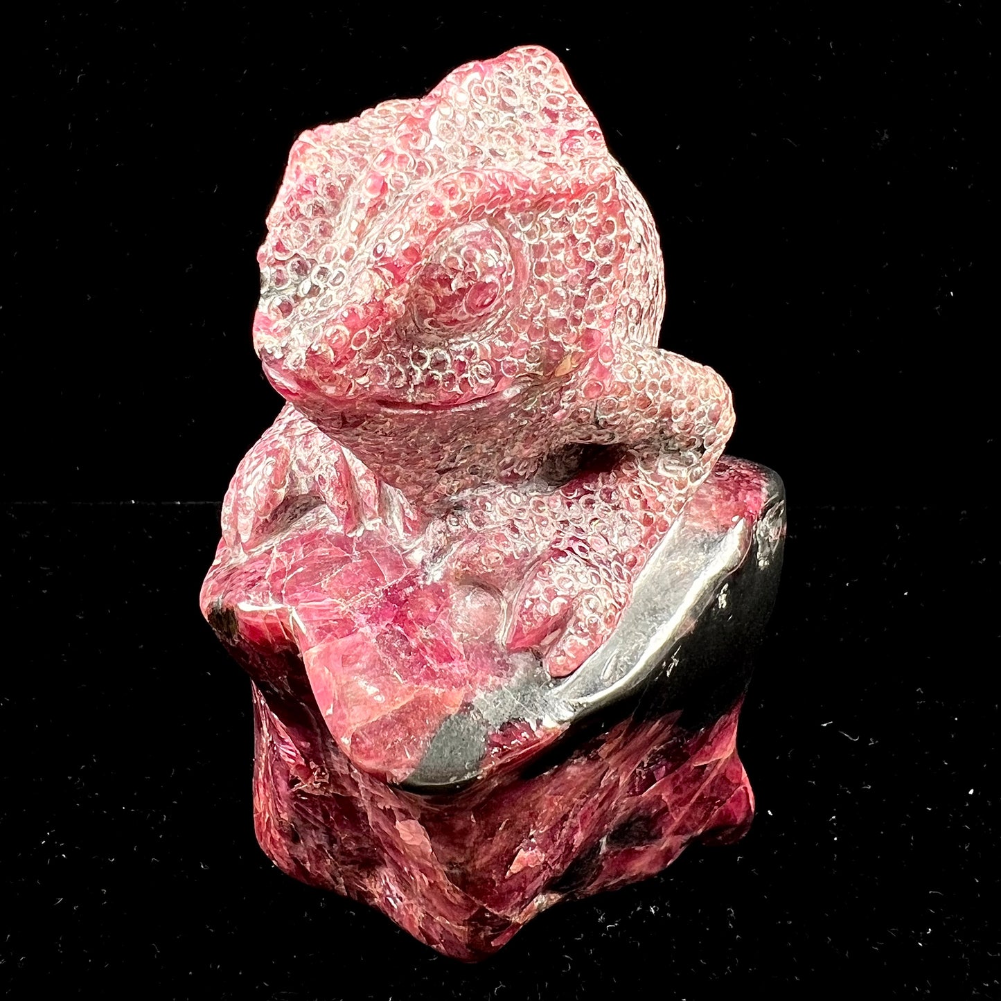 A stone chameleon lizard carved from natural rhodonite by artist, Ronald Stevens.