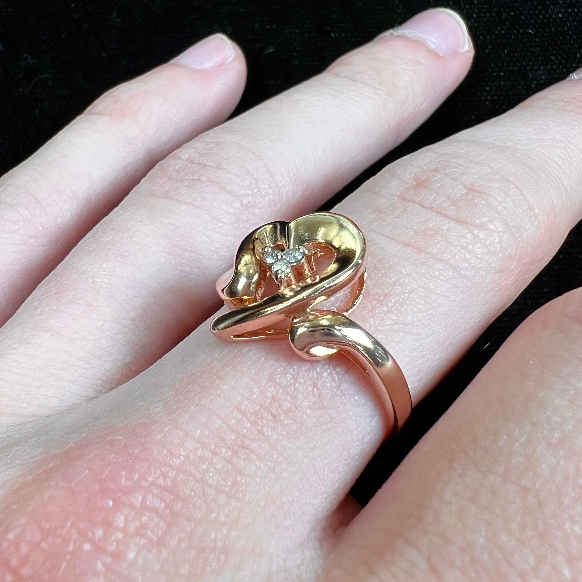 A rose gold heart ring set with three round cut diamonds.