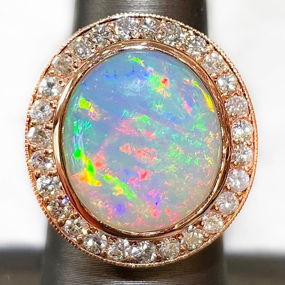 An oval cabochon cut Australian white crystal opal set in a rose gold and diamond halo ring.