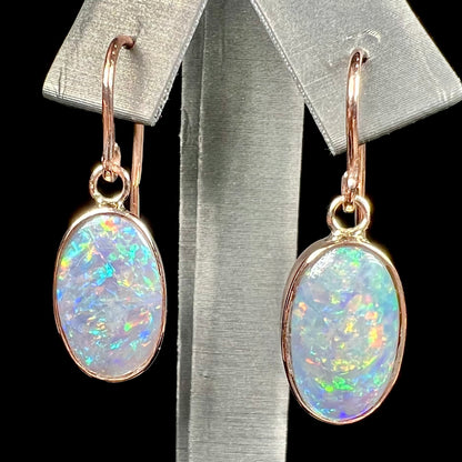 A pair of rose gold dangle earrings set with black opalized shell.