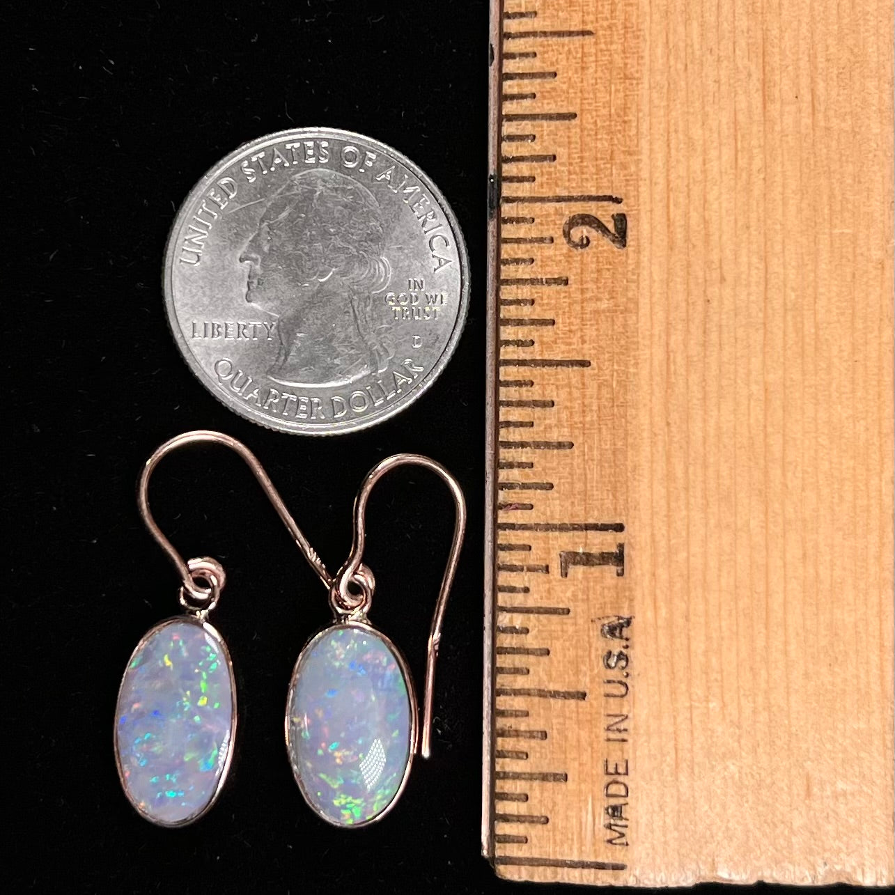 A pair of rose gold dangle earrings set with black opalized shell.