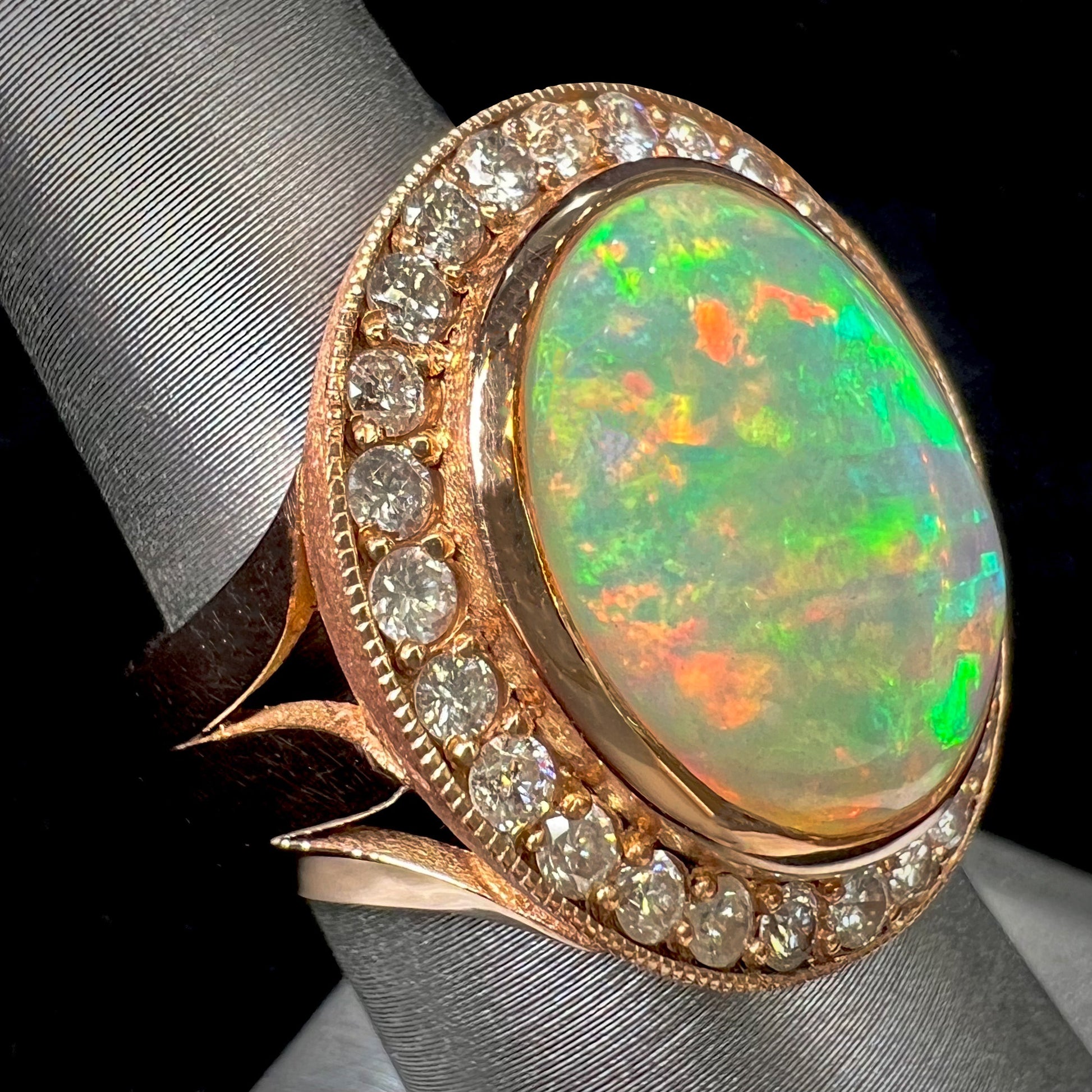 A ladies' natural crystal fire opal ring set in rose gold with a halo of round cut diamonds.