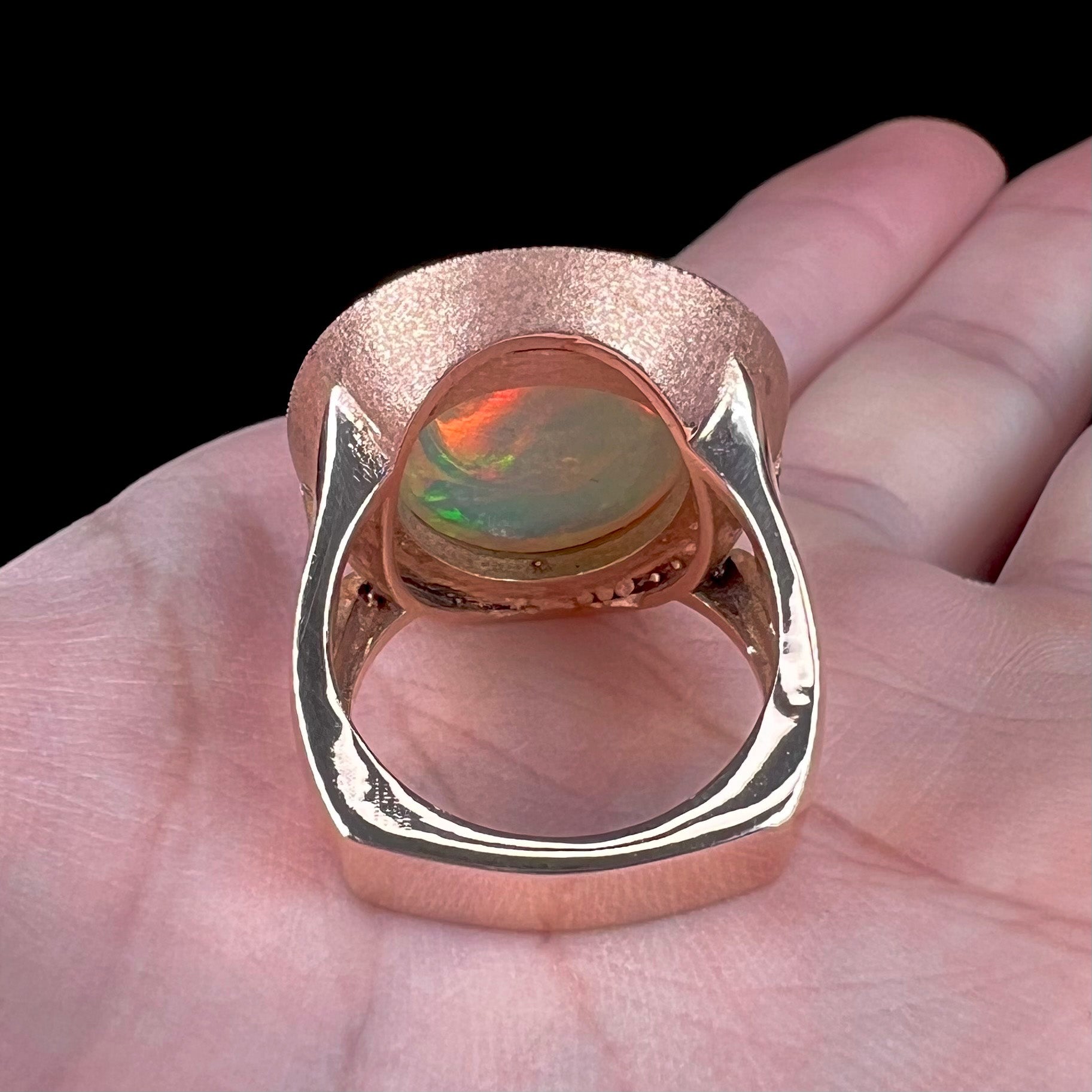 A ladies' natural crystal fire opal ring set in rose gold with a halo of round cut diamonds.