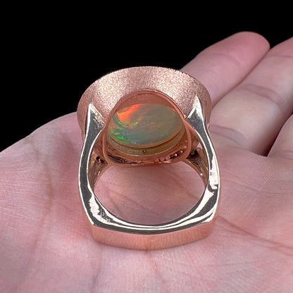 A ladies' natural crystal fire opal ring set in rose gold with a halo of round cut diamonds.