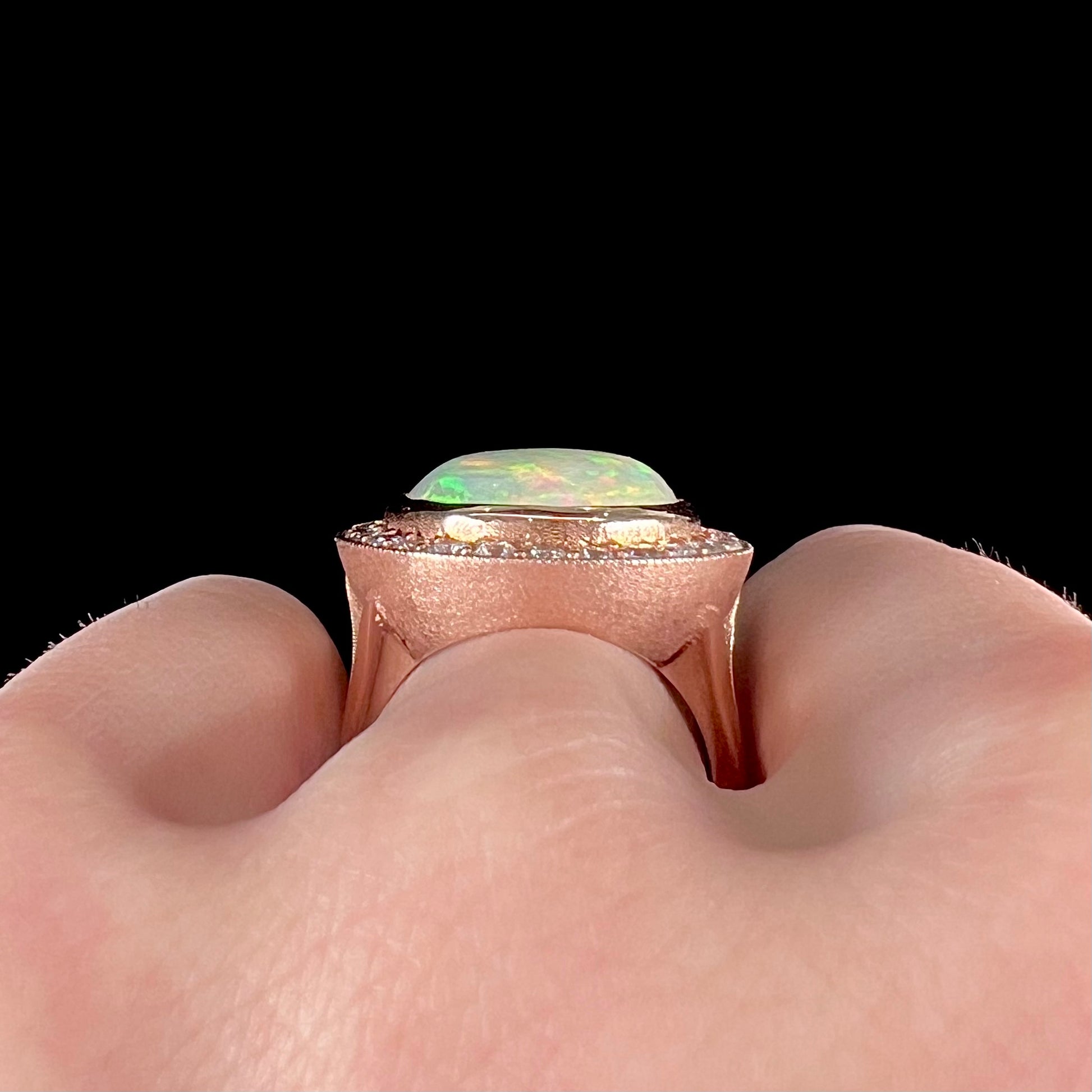 A ladies' natural crystal fire opal ring set in rose gold with a halo of round cut diamonds.