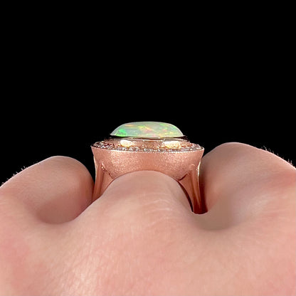 A ladies' natural crystal fire opal ring set in rose gold with a halo of round cut diamonds.