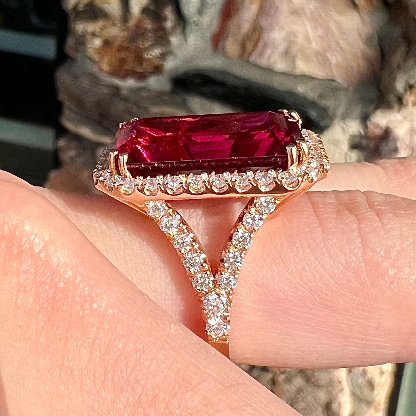 Red emerald cut rubellite tourmaline gemstone set with near flawless round cut diamonds in rose gold.