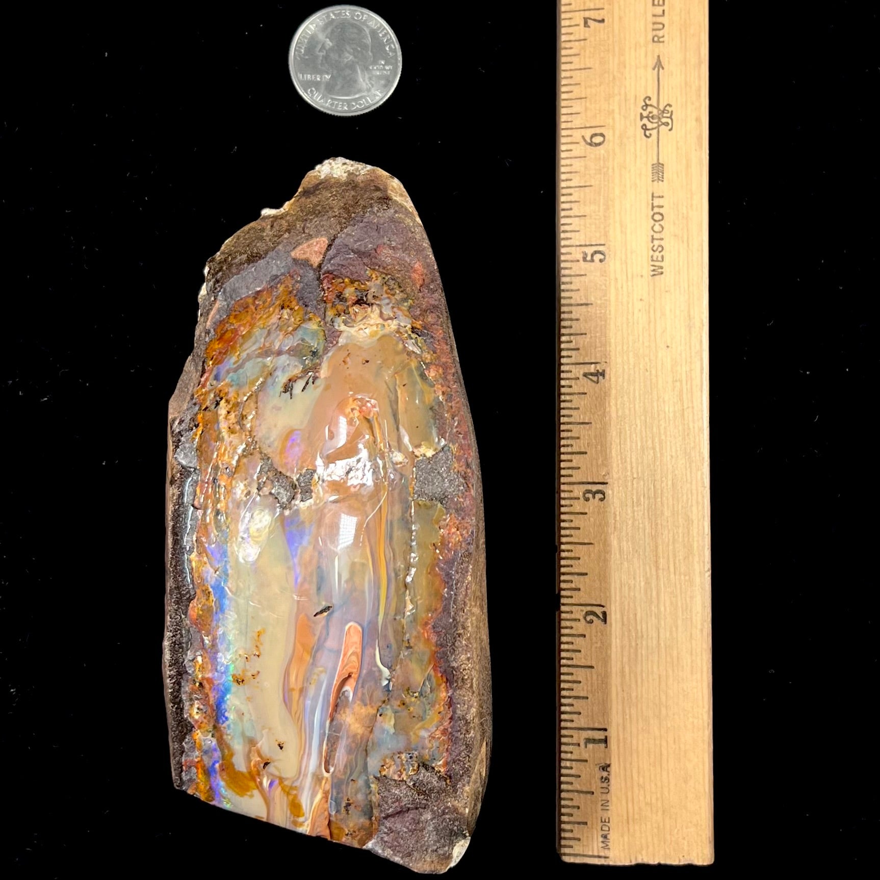 A polished Quilpie boulder opal specimen.  The stone has a stripe of bright blue, green, and purple.