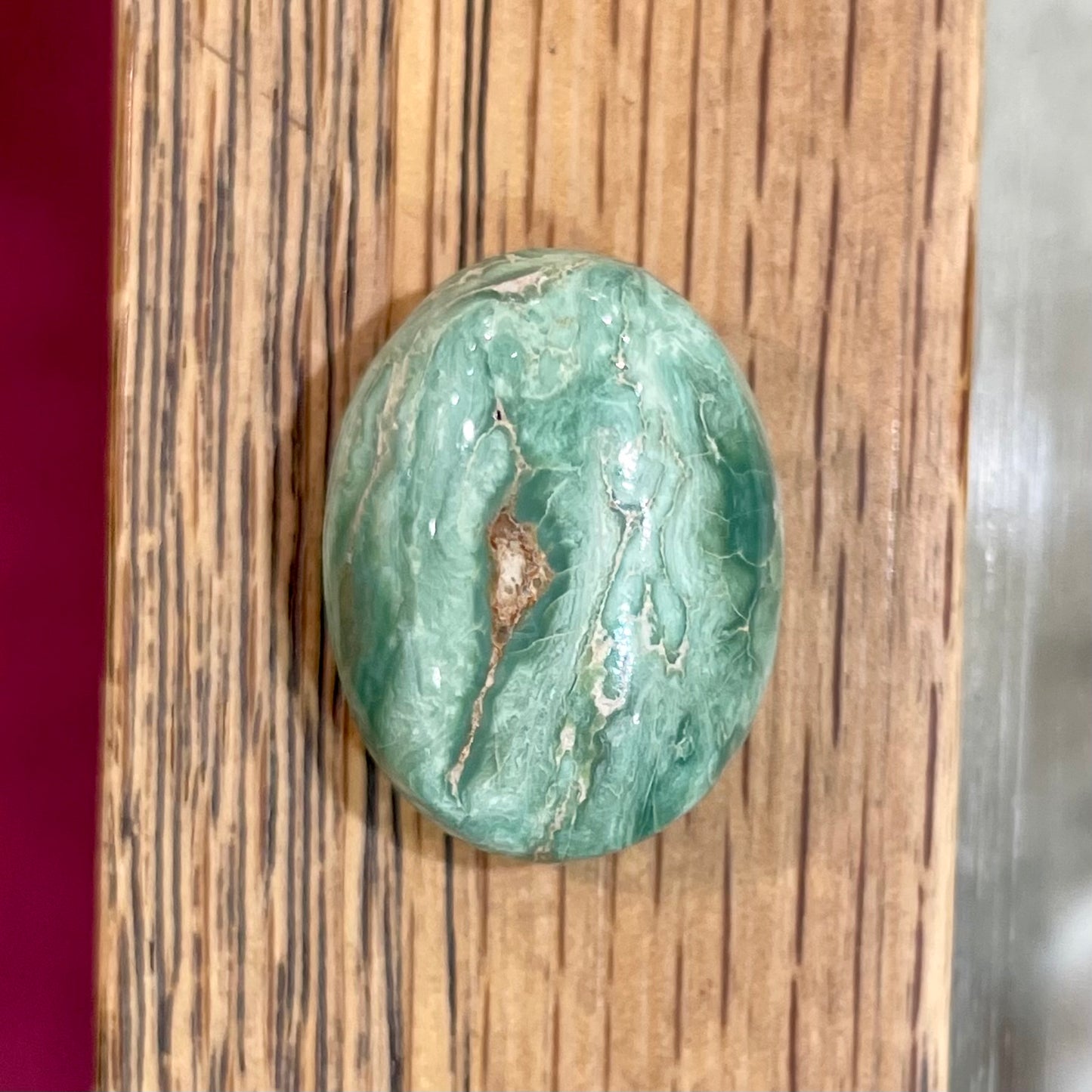 A loose, green oval cabochon cut turquoise stone from the Royston Mining District in Nevada.  Green color marbles around a light brown eye.