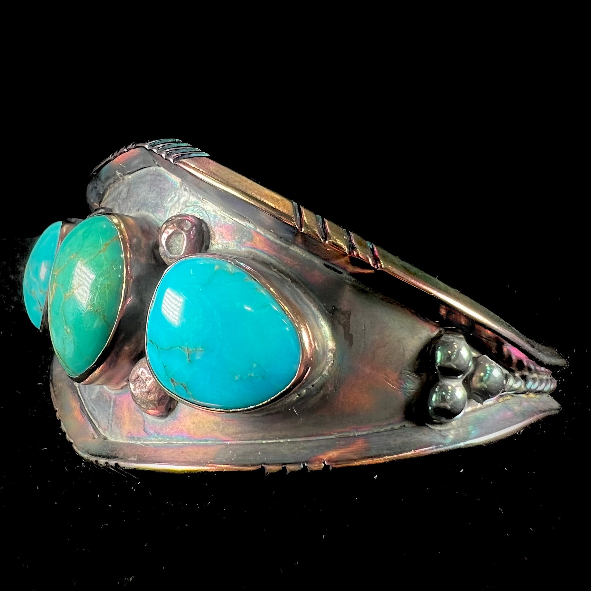 A men's Navajo three stone turquoise cuff bracelet handmade by artist, Dean Brown.  The silver has an iridescent purple patina.