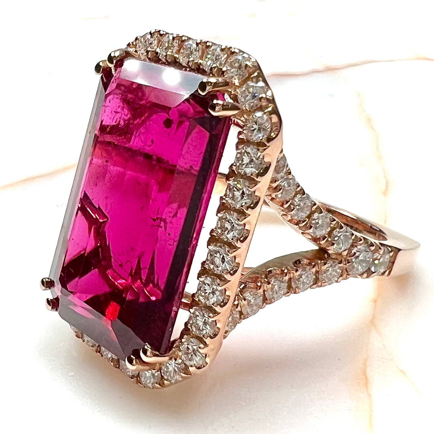 Red emerald cut rubellite tourmaline gemstone set with near flawless round cut diamonds in rose gold.