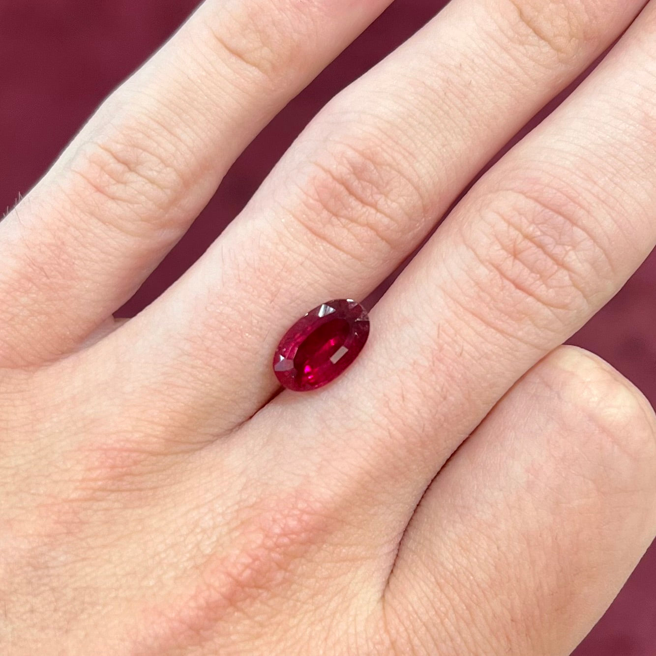 A loose, oval cut, purplish red rubellite tourmaline stone.