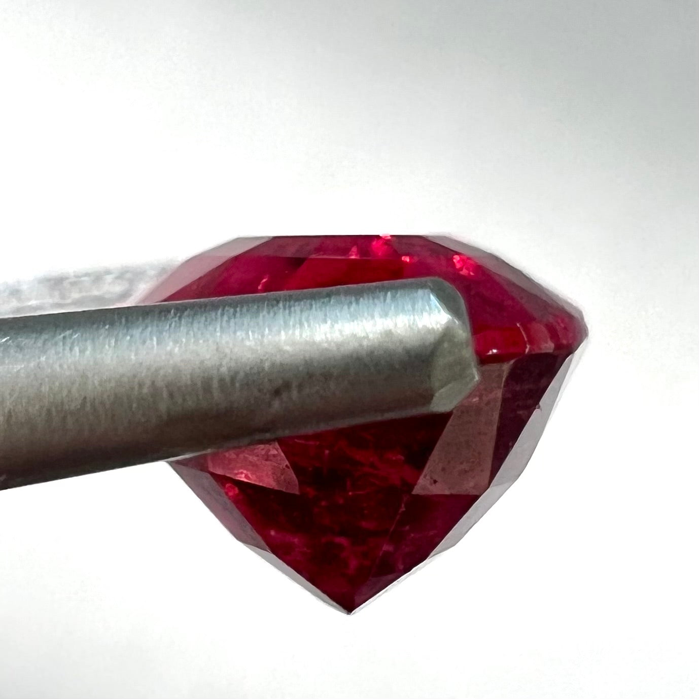 A loose, oval cut, purplish red rubellite tourmaline stone.