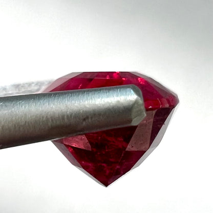 A loose, oval cut, purplish red rubellite tourmaline stone.