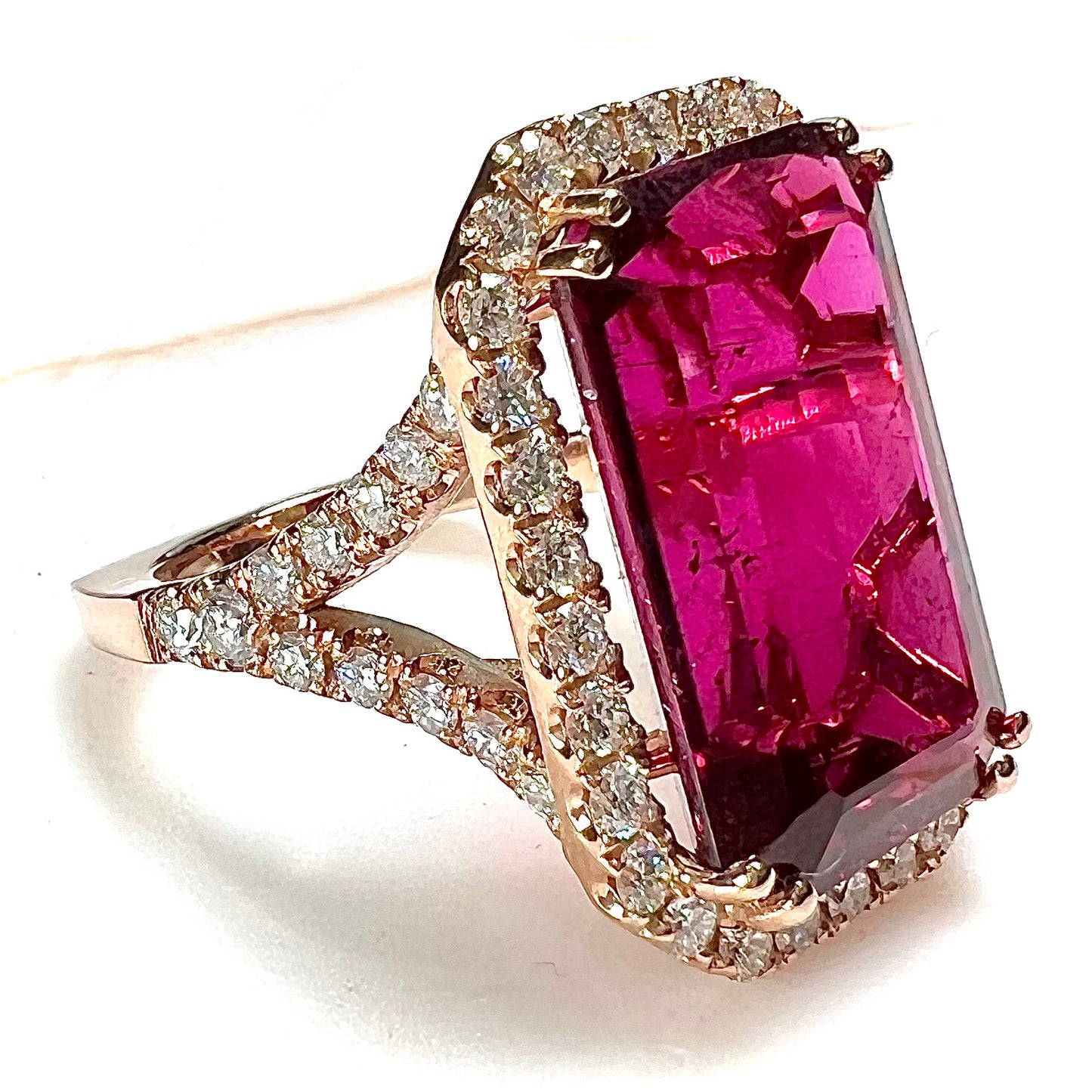 Red emerald cut rubellite tourmaline gemstone set with near flawless round cut diamonds in rose gold.