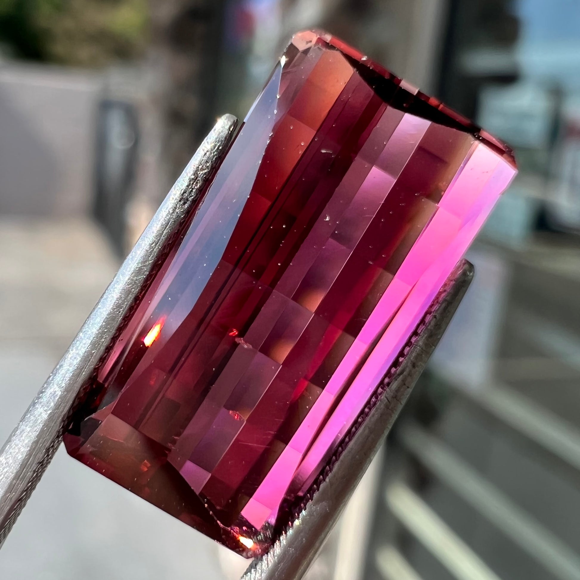A loose, fantasy cut reddish colored tourmaline.  The cut reflects light in a way that resembles digital pixels on a screen.