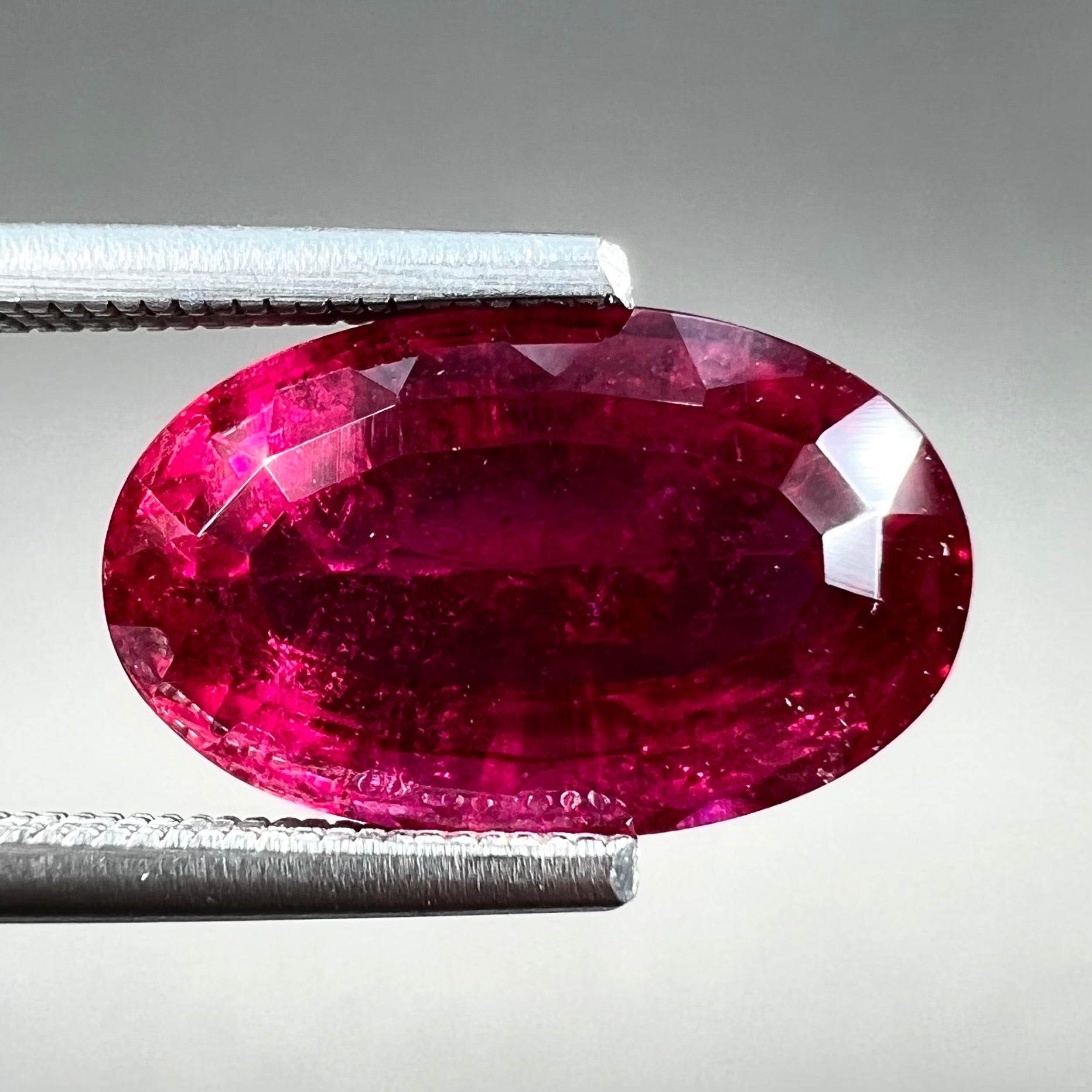 A loose, oval cut, purplish red rubellite tourmaline stone.