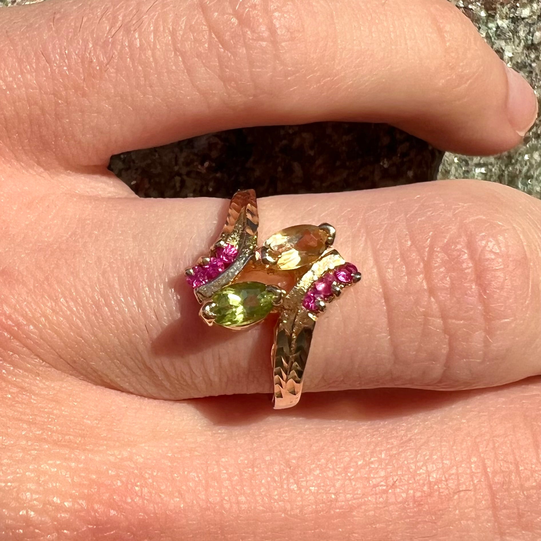A gold twisted shank ring set with a marquise cut citrine, marquise cut peridot, and round cut ruby accents.