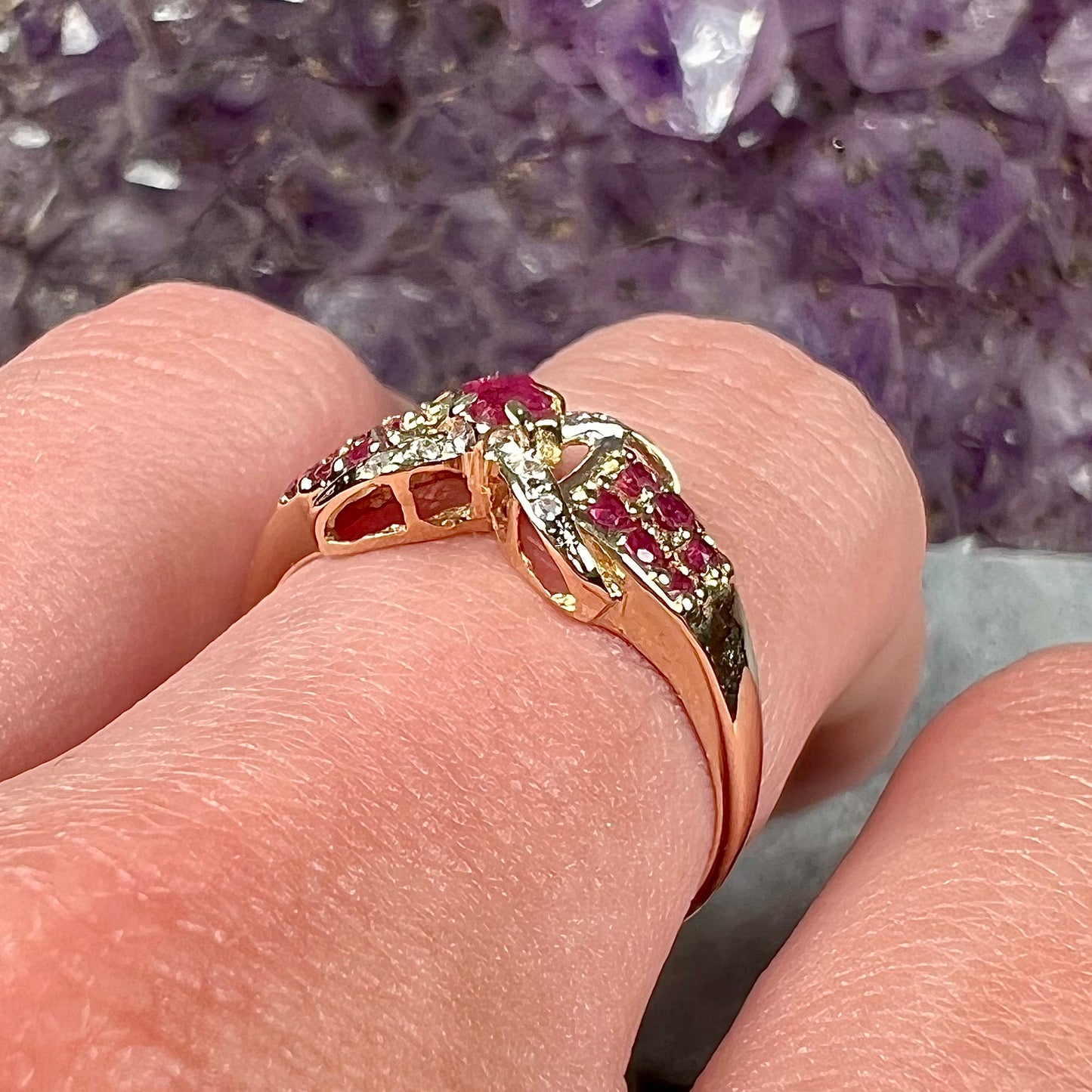 A yellow gold princess cut ruby ring set with round ruby and diamond accents.