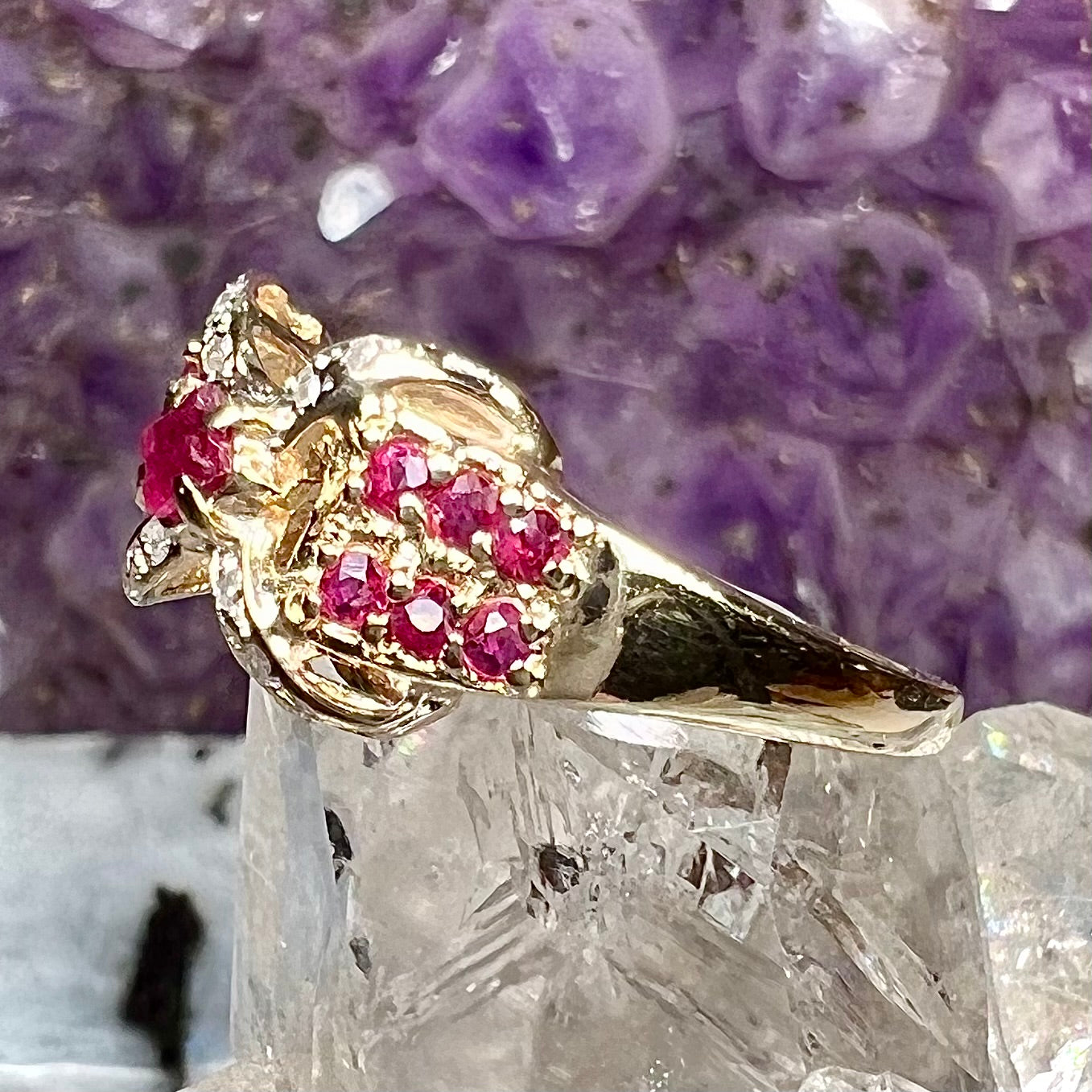 A yellow gold princess cut ruby ring set with round ruby and diamond accents.
