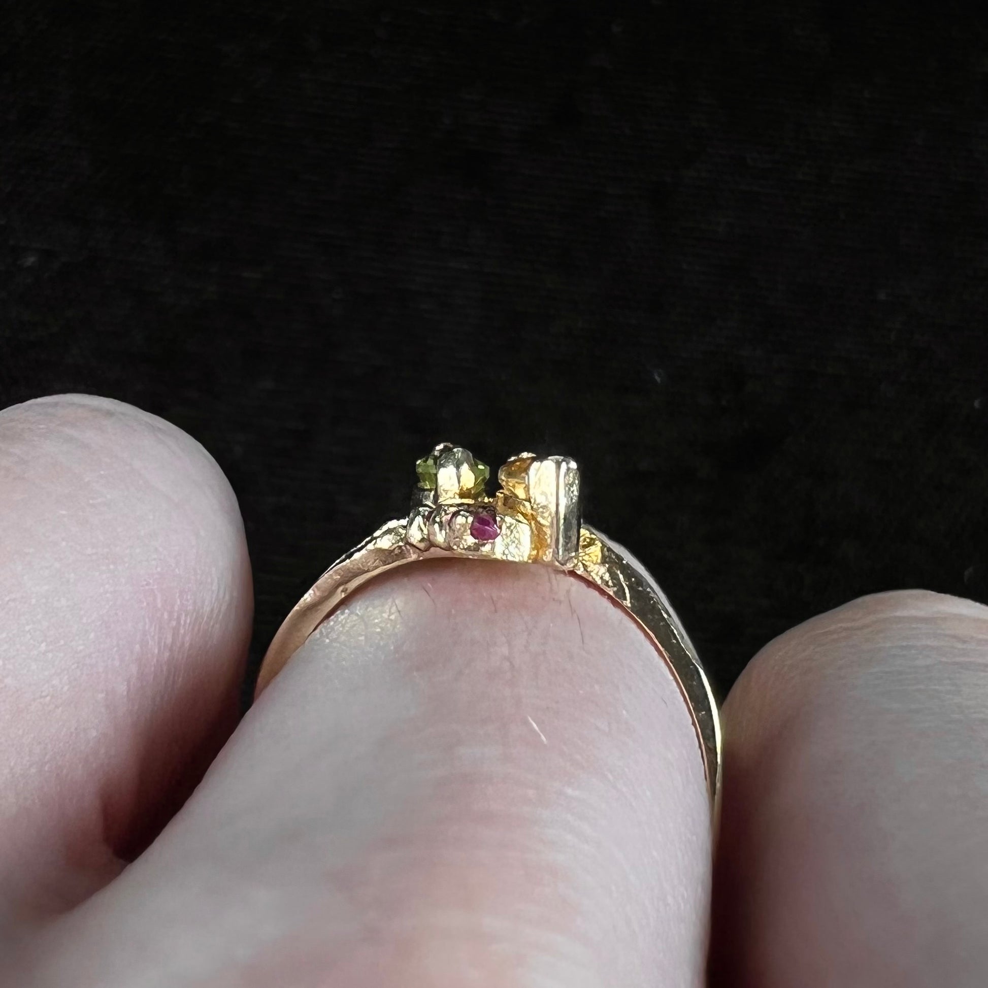 A gold twisted shank ring set with a marquise cut citrine, marquise cut peridot, and round cut ruby accents.