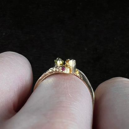 A gold twisted shank ring set with a marquise cut citrine, marquise cut peridot, and round cut ruby accents.
