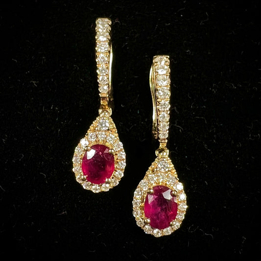 A pair of ruby and diamod halo dangle earrings cast in 14k yellow gold.