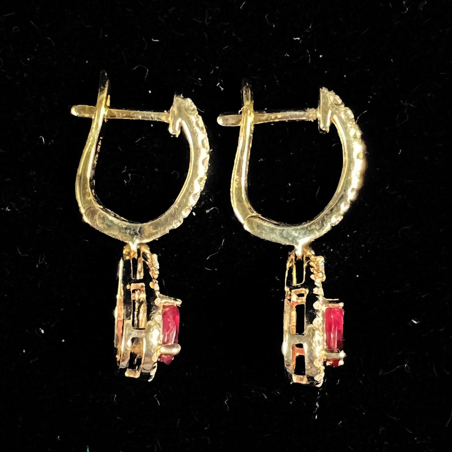 A pair of ruby and diamod halo dangle earrings cast in 14k yellow gold.