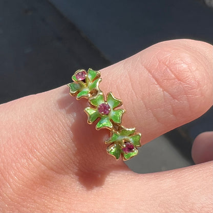 A gold ladies' ring in the motif of three flowers set with round ruby centers and green enameled petals.