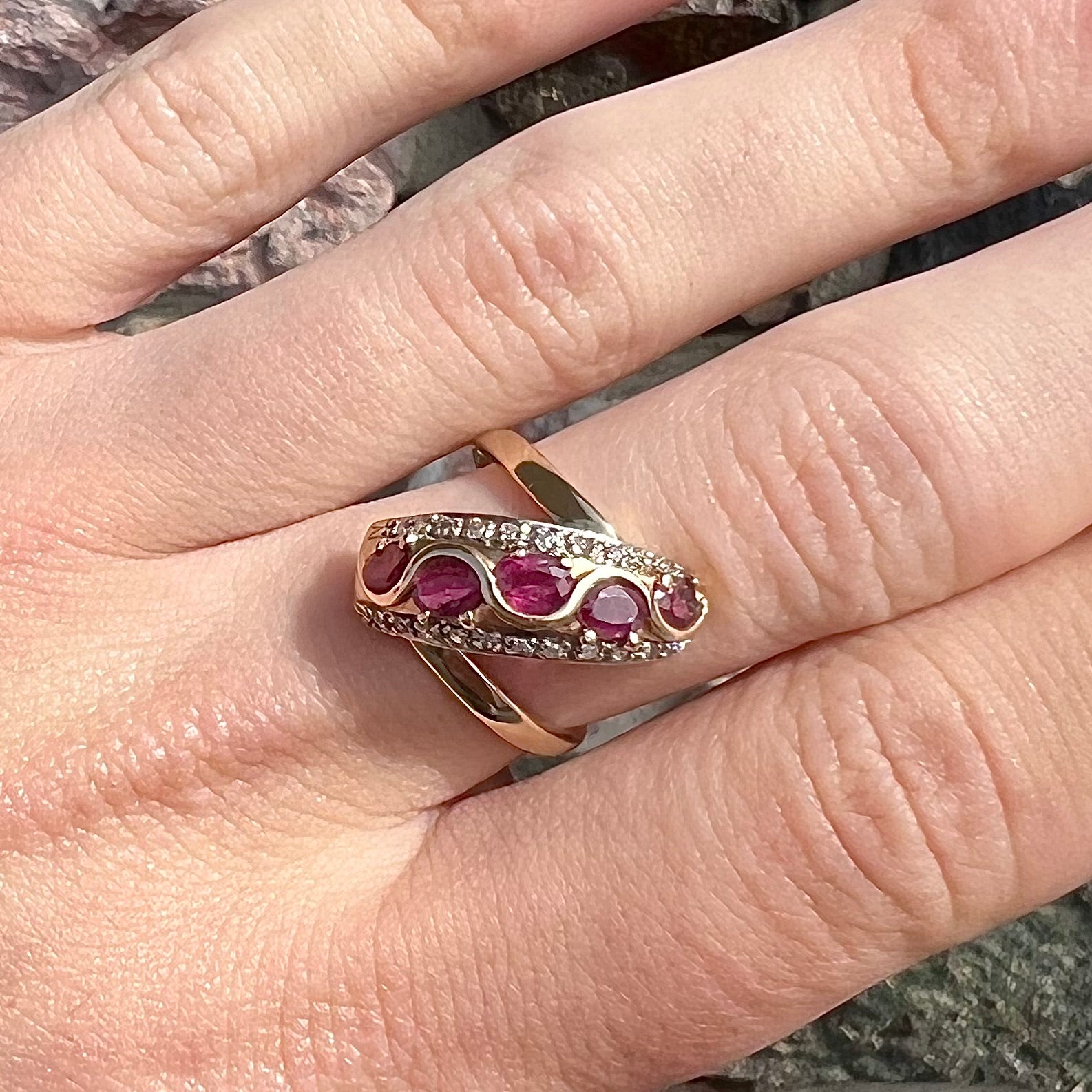 A custom freeform design yellow gold twisted shank ring set with five oval cut rubies and small round diamonds.