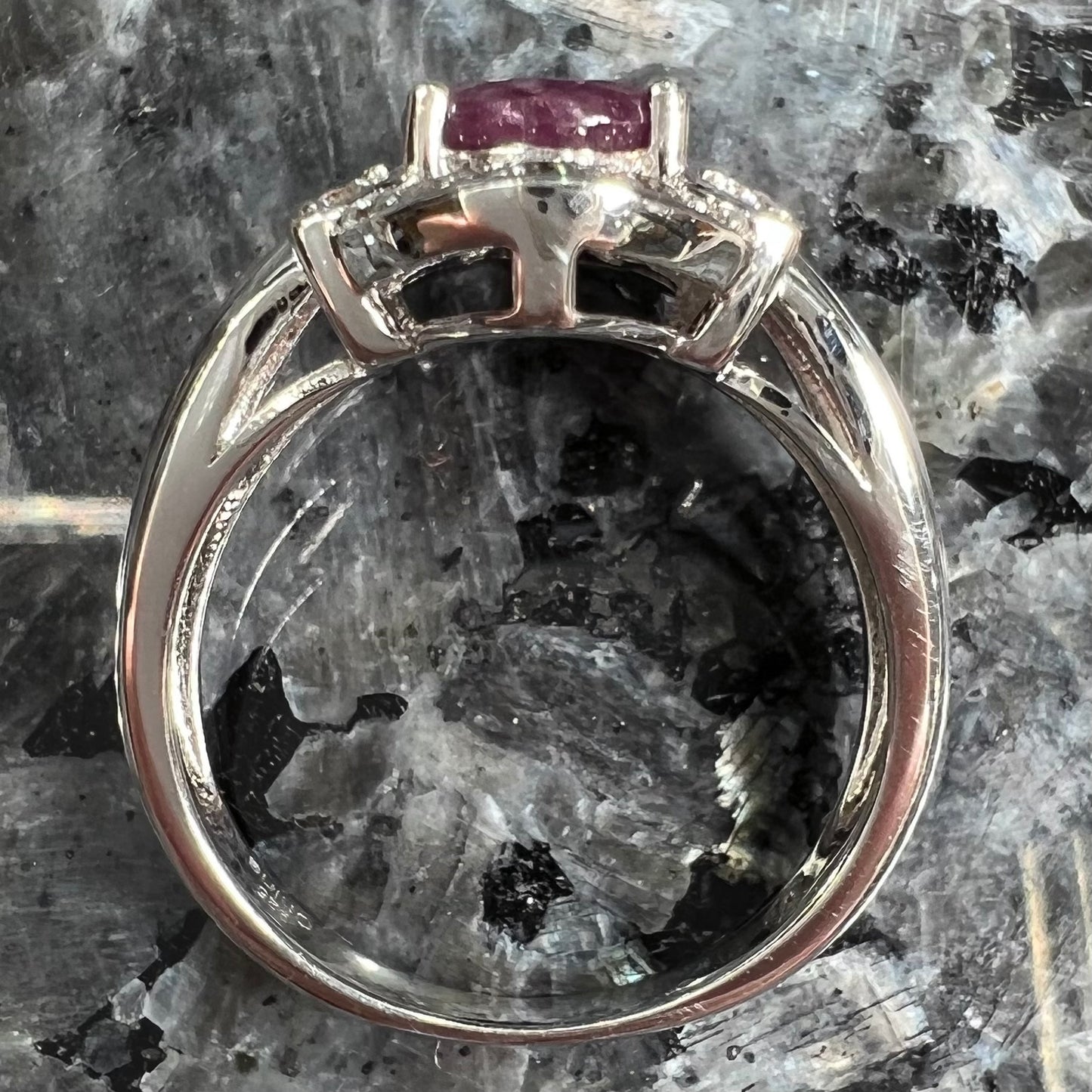 A natural, faceted oval cut ruby ring cast in sterling silver and set with cubic zirconia accents.