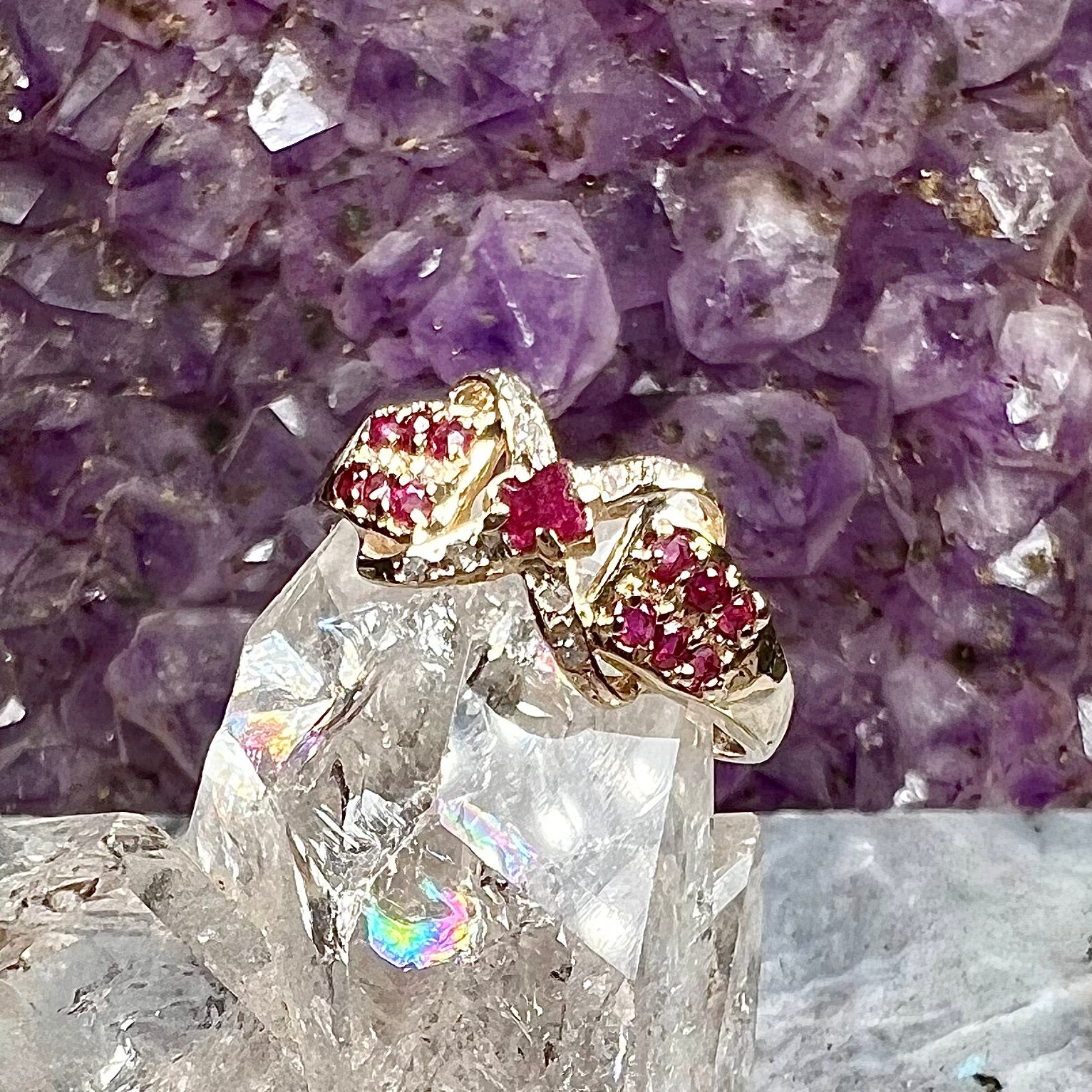 A yellow gold princess cut ruby ring set with round ruby and diamond accents.