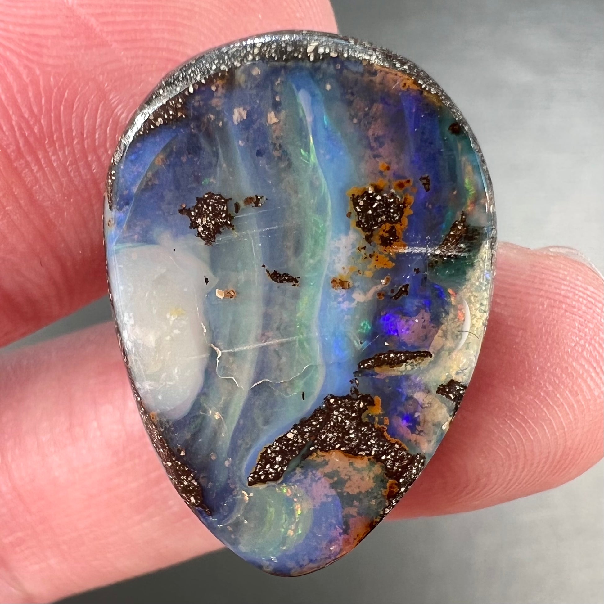 A loose, pear shaped Australian boulder opal.  The pattern on the opal resembles the face of a very sad man.