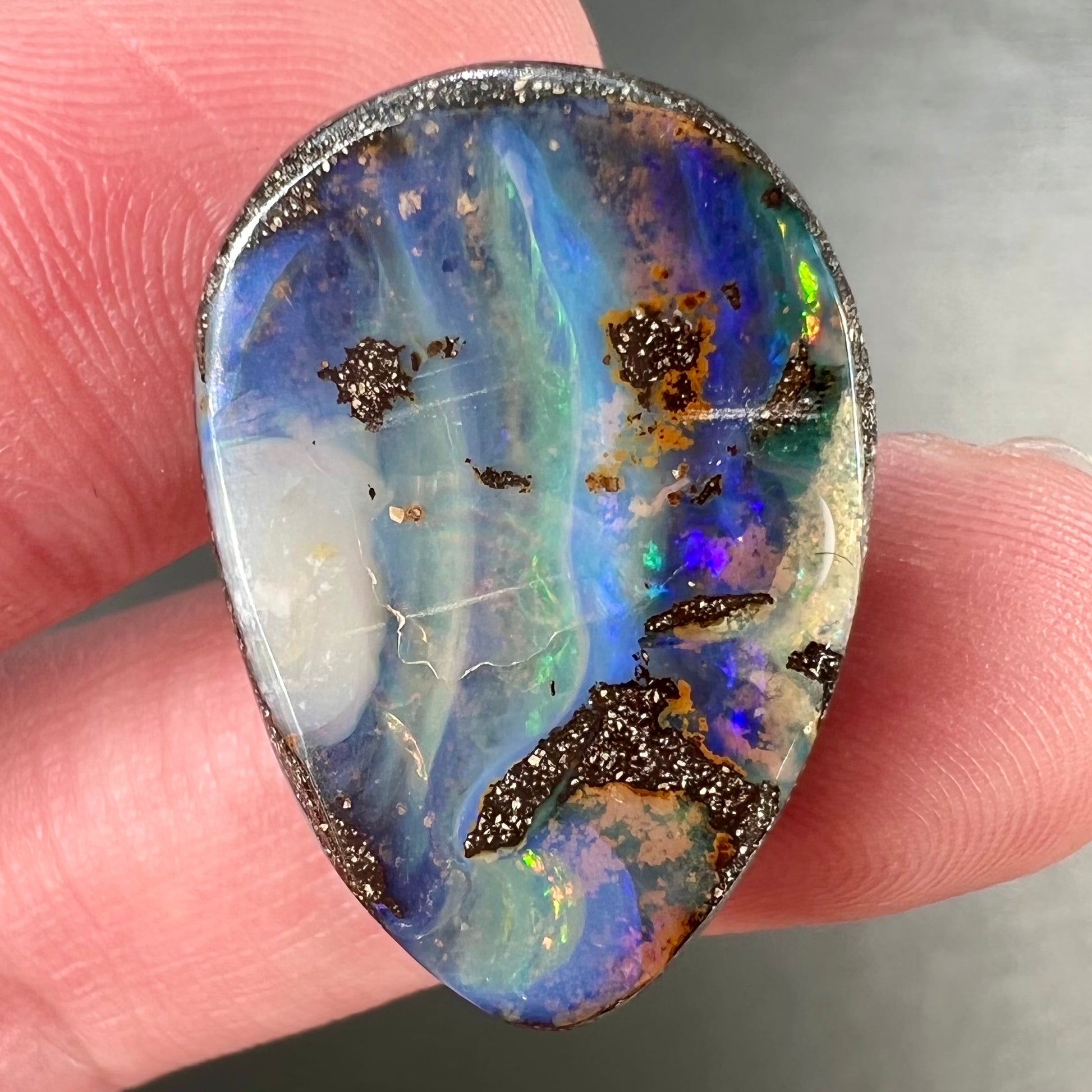 A loose, pear shaped Australian boulder opal.  The pattern on the opal resembles the face of a very sad man.