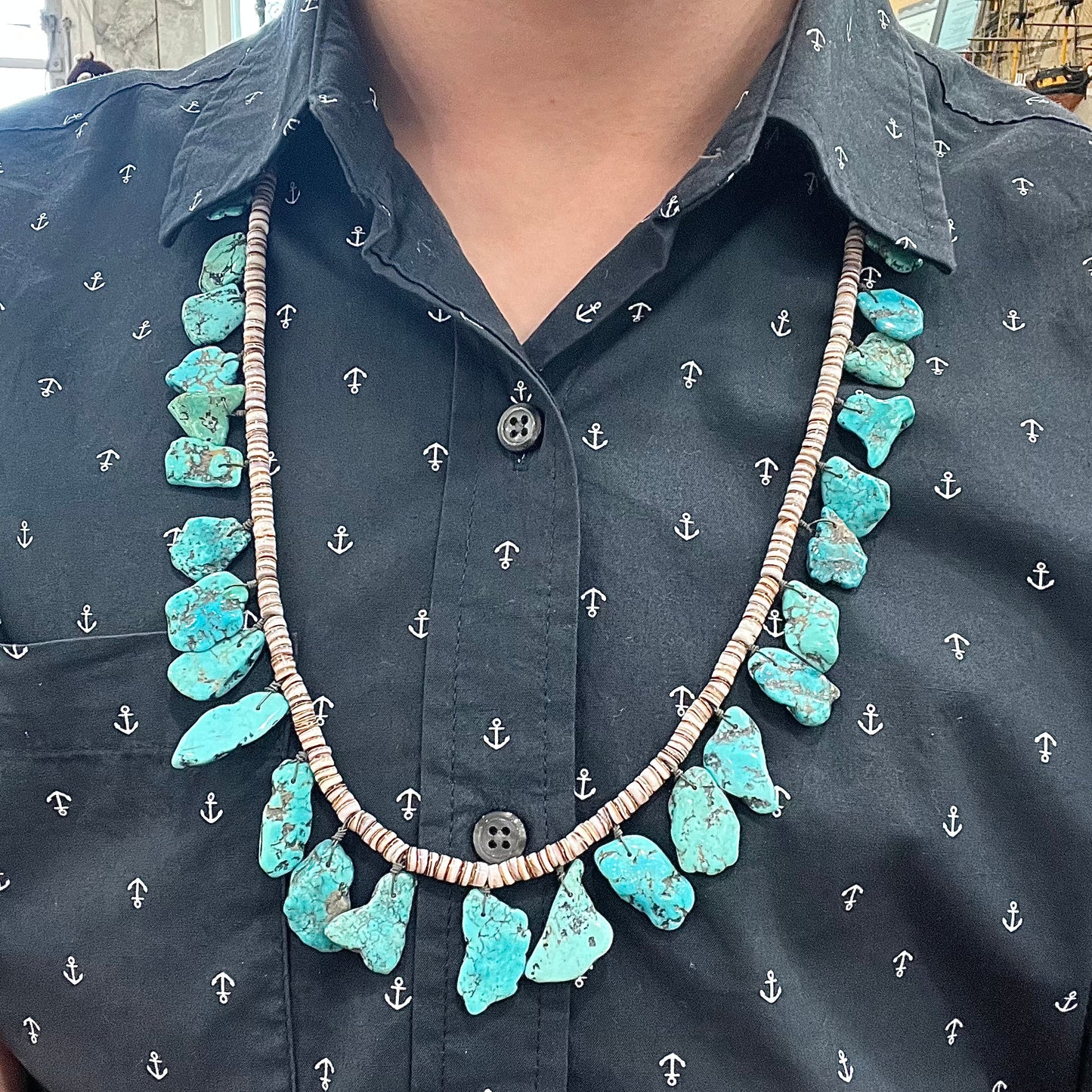 A Santo Domingo puka shell bead necklace with drilled turquoise nuggets attached.