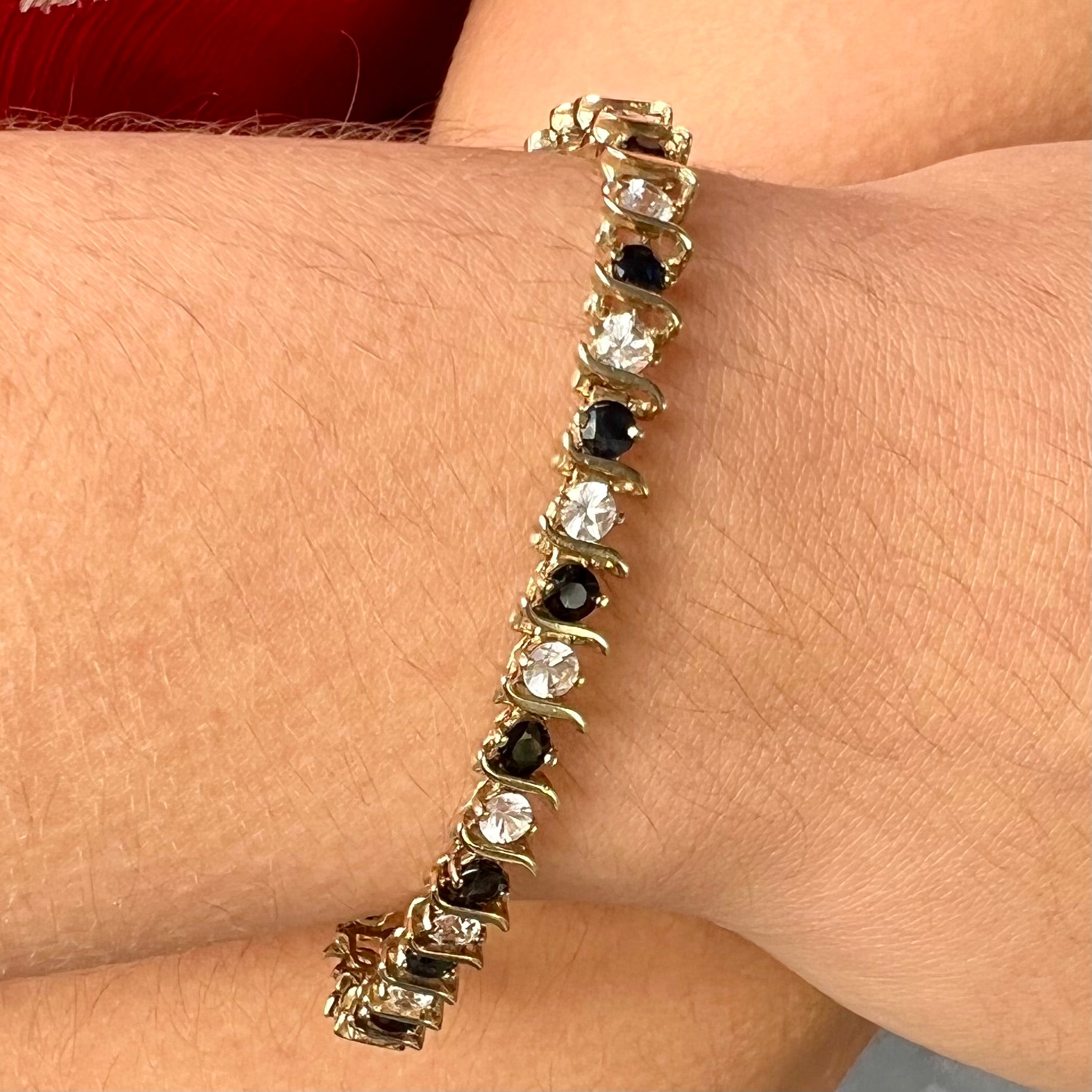 A yellow gold tennis bracelet set with round midnight blue and white natural sapphires.