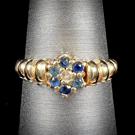 A ladies' yellow gold cluster ring set with round blue sapphires and a round diamond.