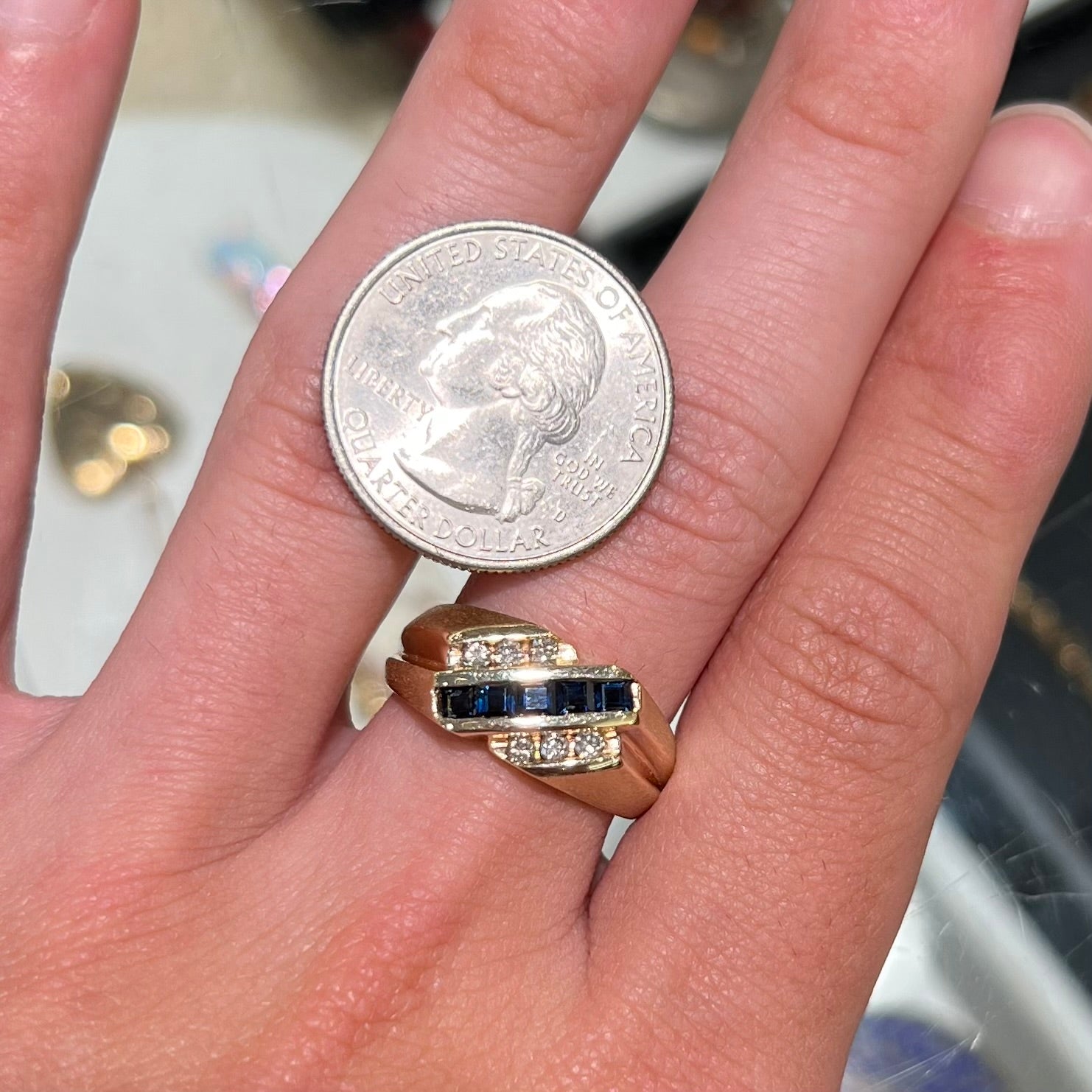 A men's yellow gold ring channel set with princess cut blue sapphires and diamonds.
