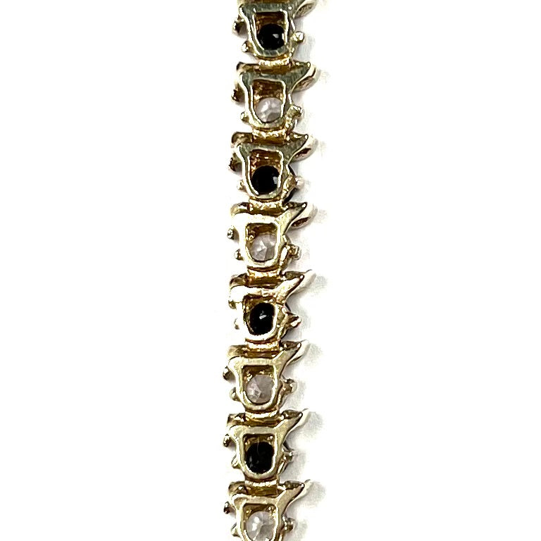 A yellow gold tennis bracelet set with round midnight blue and white natural sapphires.