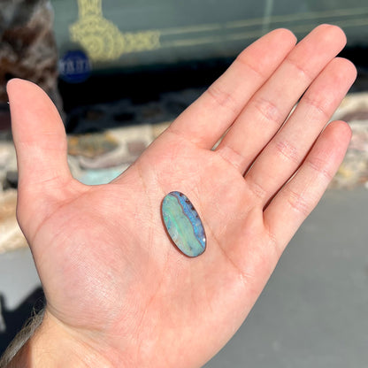 A loose, oval cabochon cut boulder opal stone from Queensland, Australia.
