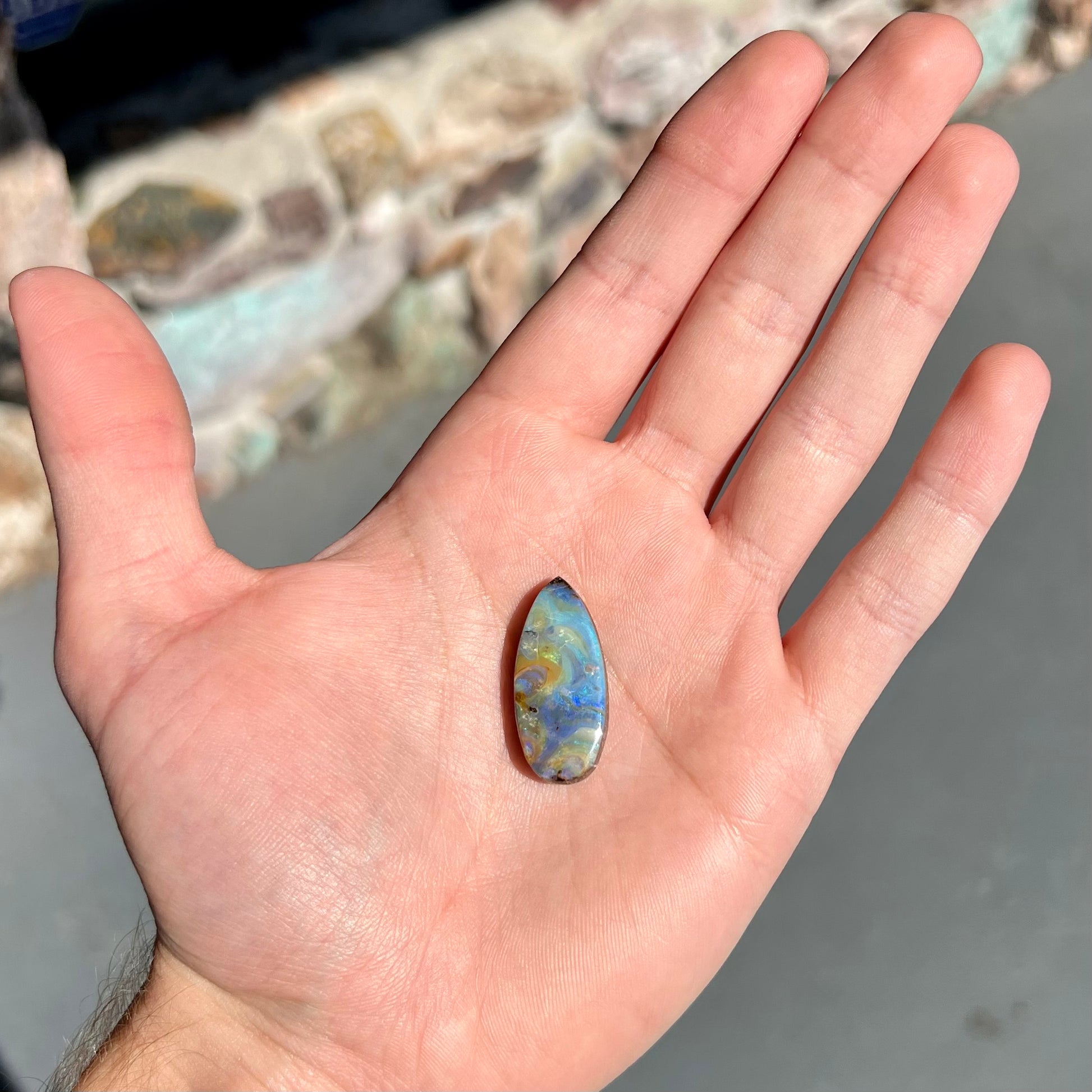 A loose, natural, pear shaped boulder opal stone from Quilpie, Australia.