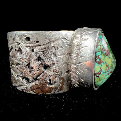 A men's sterling silver cuff bracelet infused with copper and set with a green turquoise stone from Carico Lake, Nevada.
