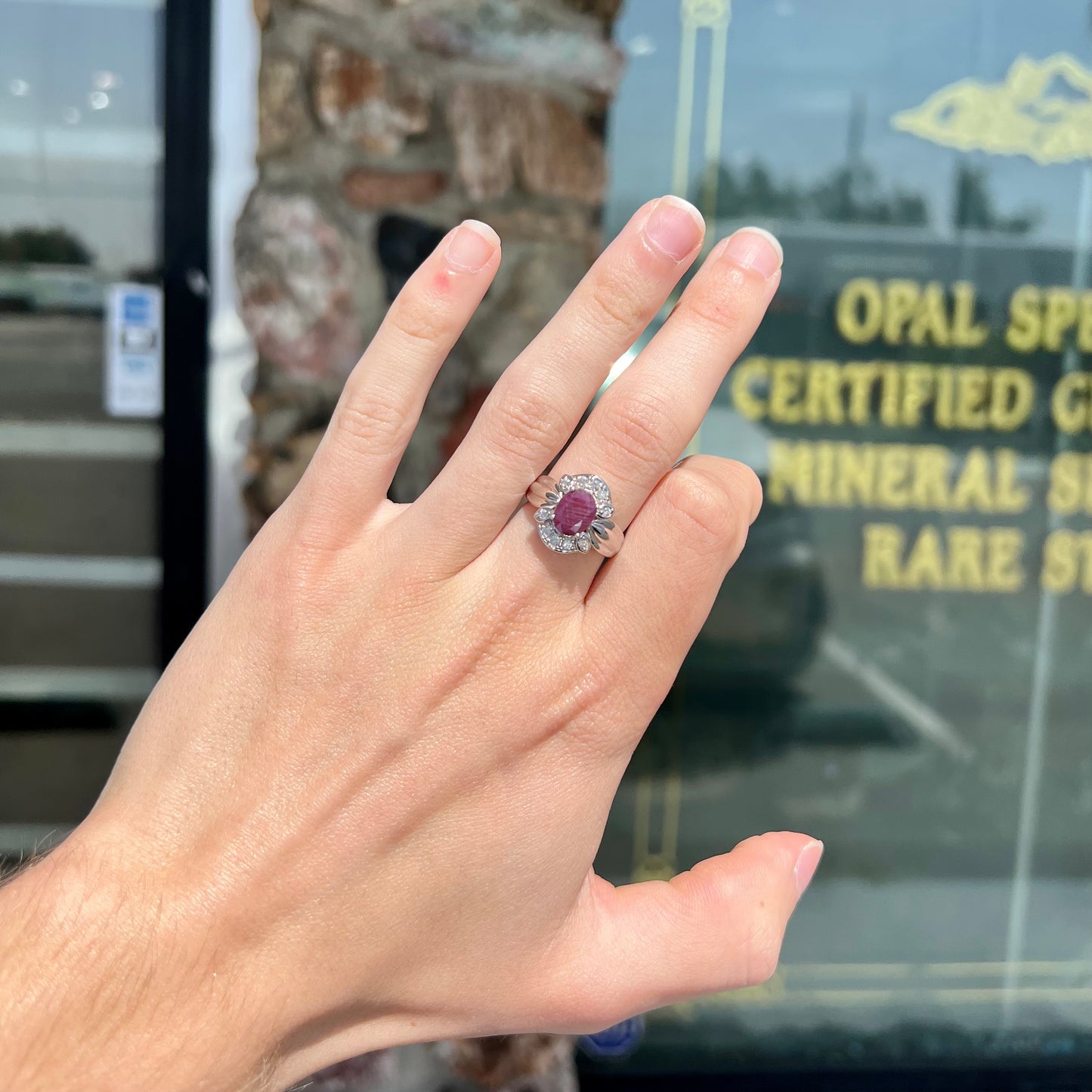 A natural, faceted oval cut ruby ring cast in sterling silver and set with cubic zirconia accents.